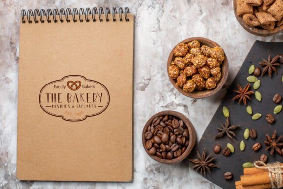 70+ Food Logo Fonts for Restaurants, Cafes, and Food Brands 146 Rustic bakery logo on a notepad surrounded by baked goods and spices.
