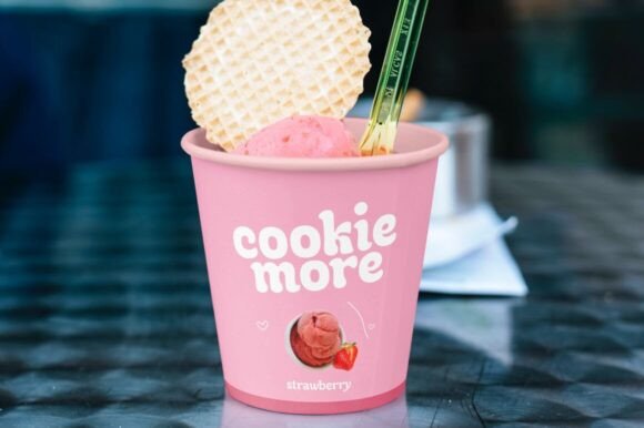 70+ Food Logo Fonts for Restaurants, Cafes, and Food Brands 28 Pink ice cream cup with the text 'cookie more' and a waffle cone on top.