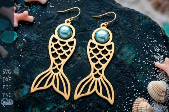 99+ Laser Cut Wood Projects To Sell From Home 121 Gold fish-shaped earrings with a blue gemstone, showcasing a laser cut wood design.