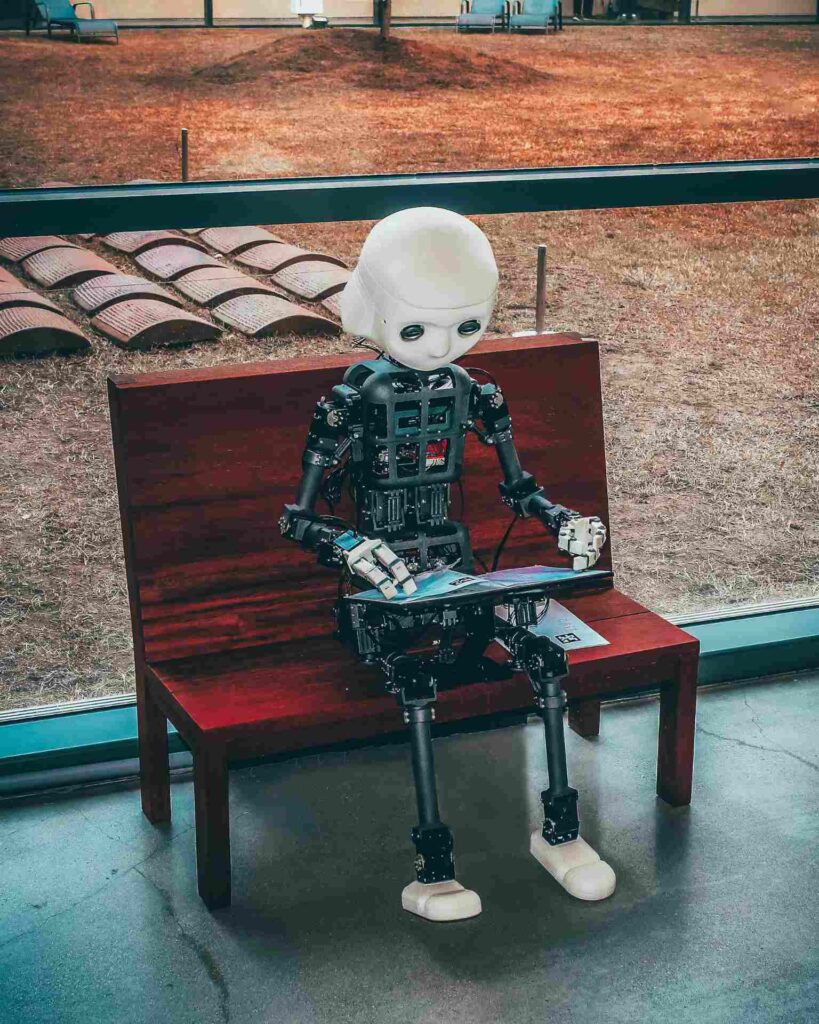 Why Clients Sometimes Choose AI Designs Over Better Custom Work 3 A small humanoid robot with a white head and mechanical body sitting on a wooden bench and looking at a tablet