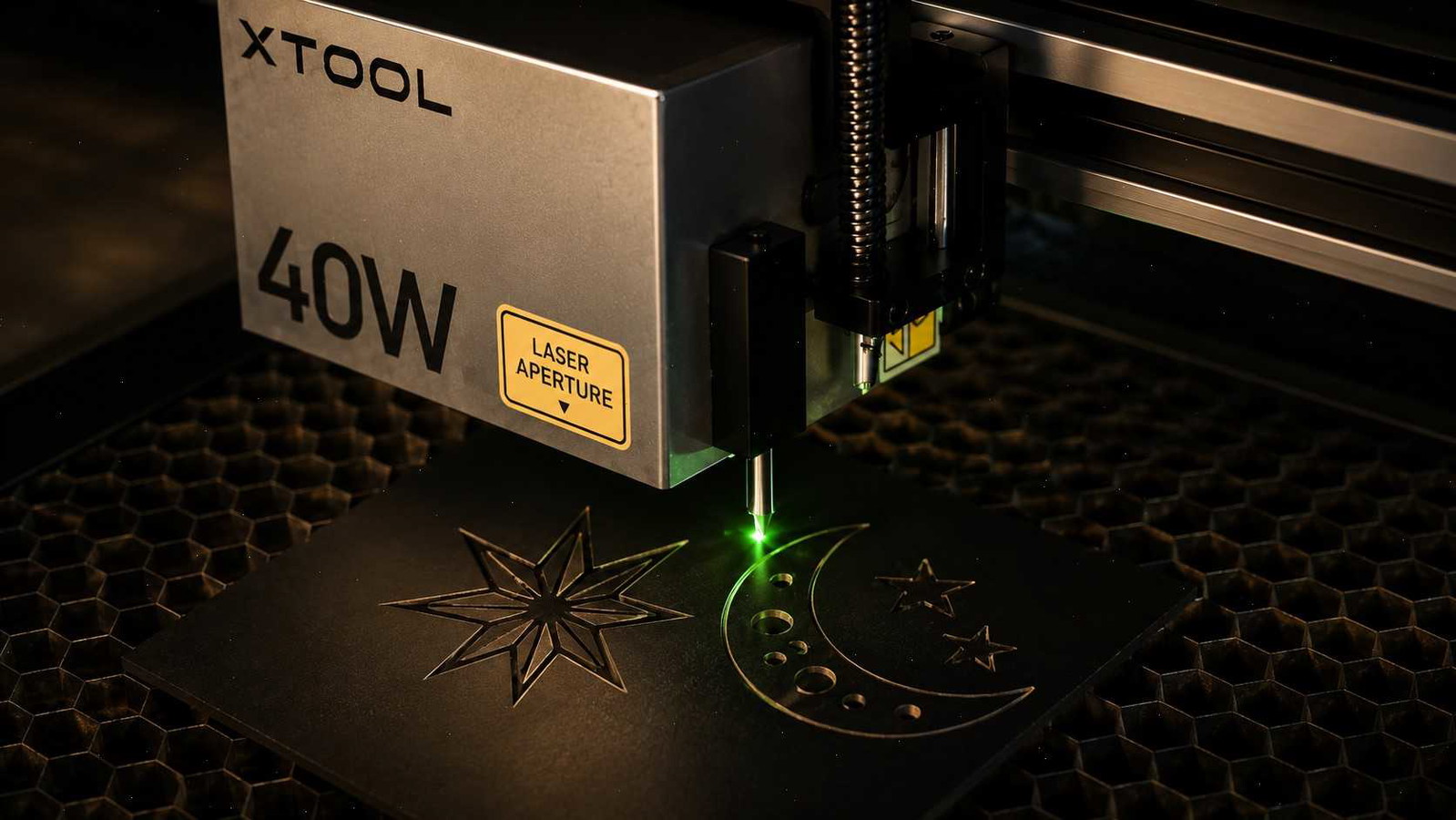xTool 40W laser engraver head with a green beam engraving celestial patterns onto a dark surface