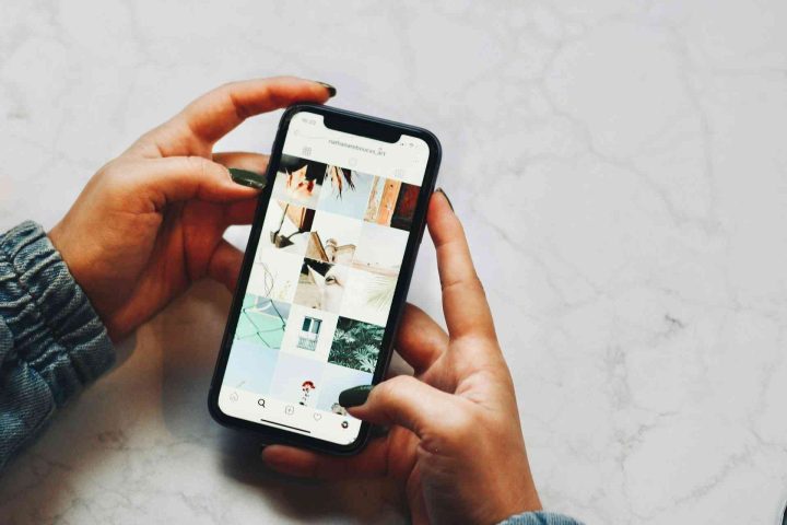 Hands holding a smartphone displaying an Instagram grid of art photos