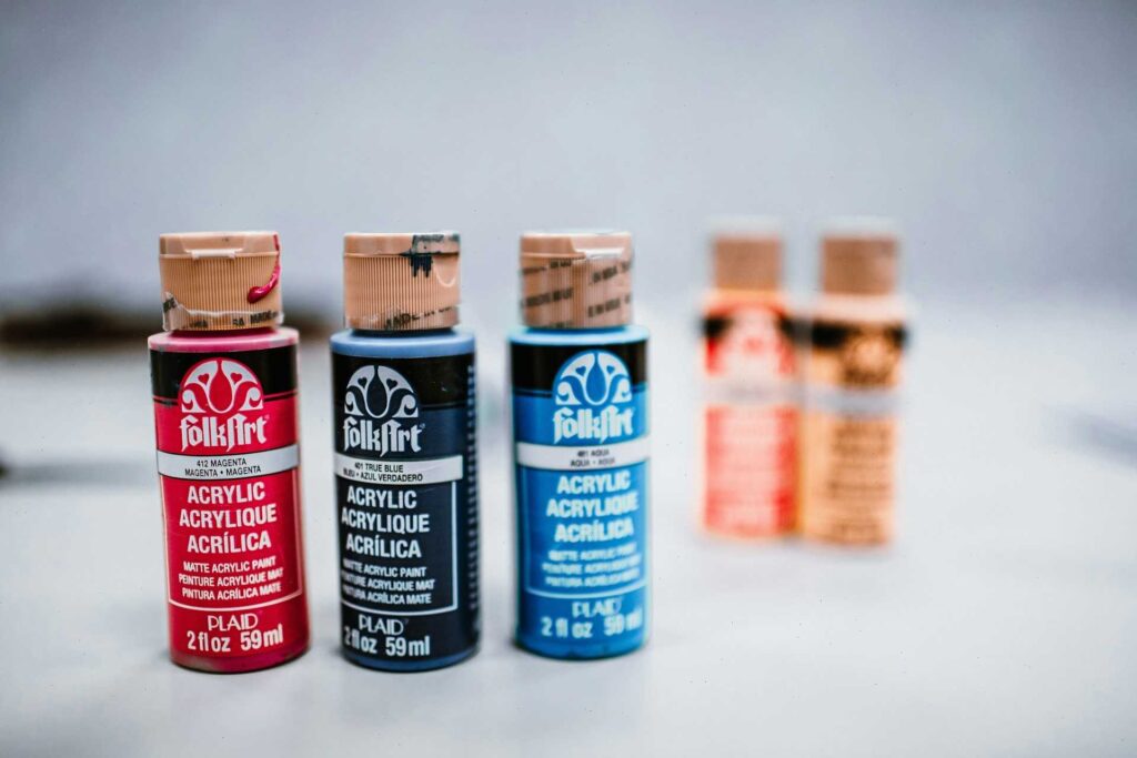 How to Paint Laser Cut Wood: 5 Methods Makers Actually Use 3 Three bottles of FolkArt matte acrylic paint in magenta, blue, and aqua
