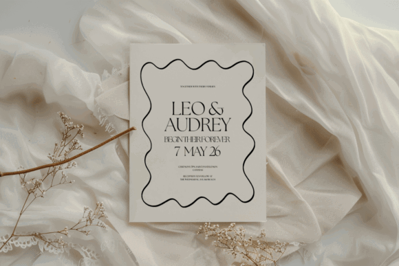 17 Wedding Invitation Template Ideas You Can Customize 8 Minimalist black wave wedding invitation with names and date on a soft fabric background.